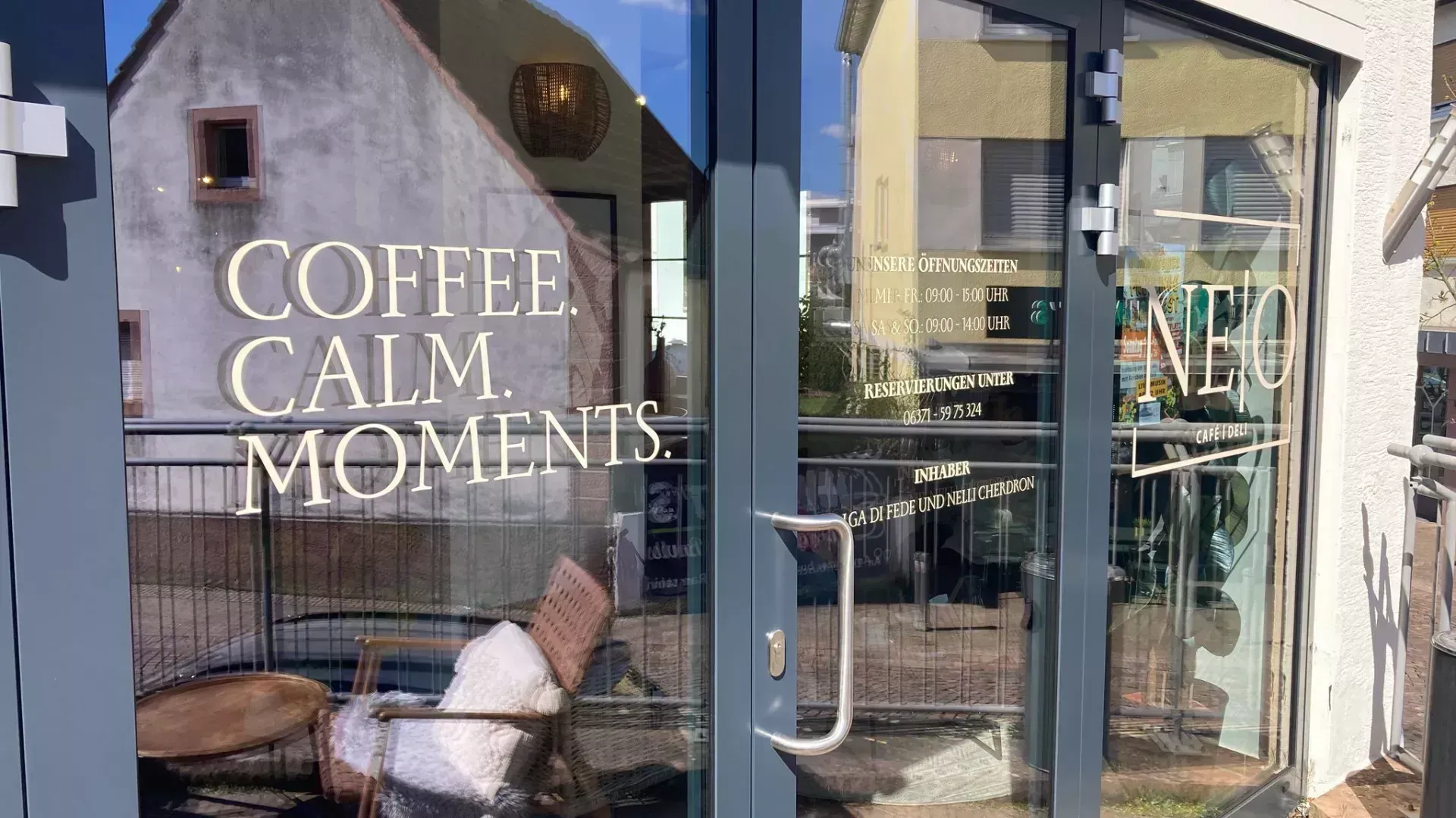 Moderne Schaufensterfolierung beim Café Neo in Ramstein mit dem Schriftzug COFFEE CALM MOMENTS und Öffnungszeiten in heller Plottfolie.