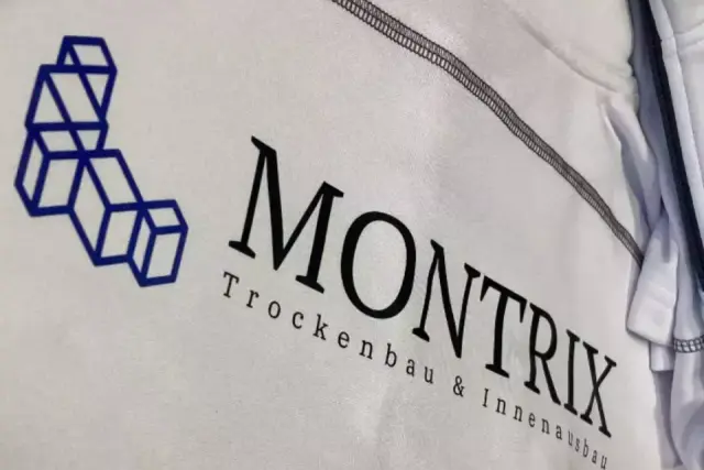 Nahaufnahme weißer Arbeitskleidung mit blau-schwarzem MONTRIX-Trockenbau-Logo im Siebdruck